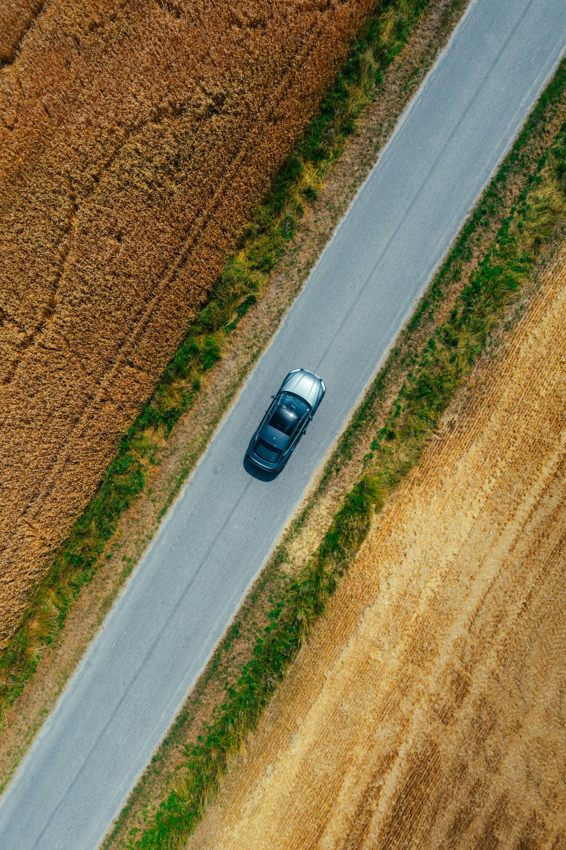 an aerial view of a car driving down a country road